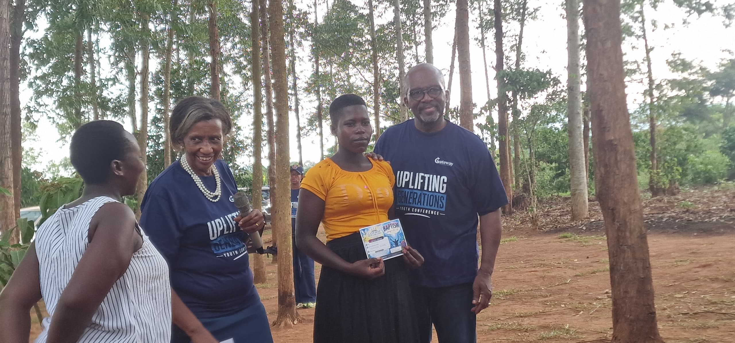 Pastor Agatha and Pastor Gladstone presenting a baptism certificate to a young woman