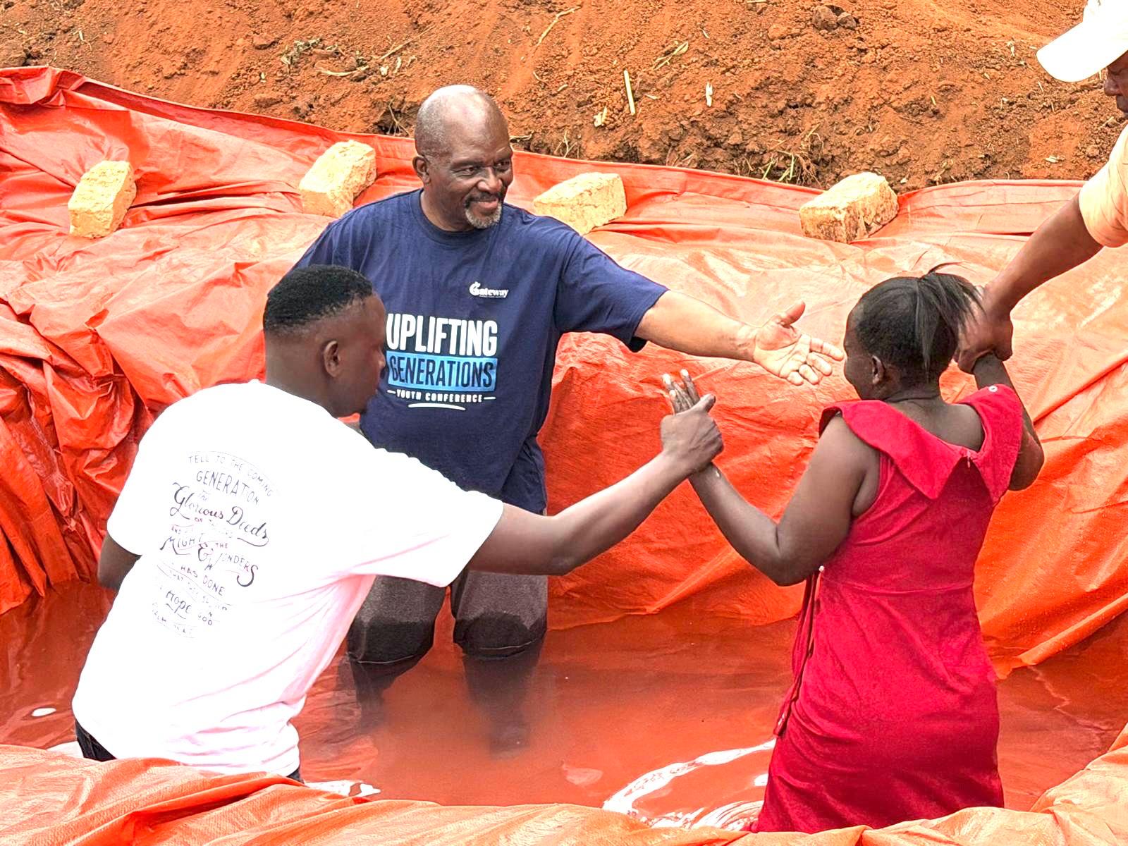 Pastor Gladstone Johnson welcoming a young woman into the baptism pool in Tema Village